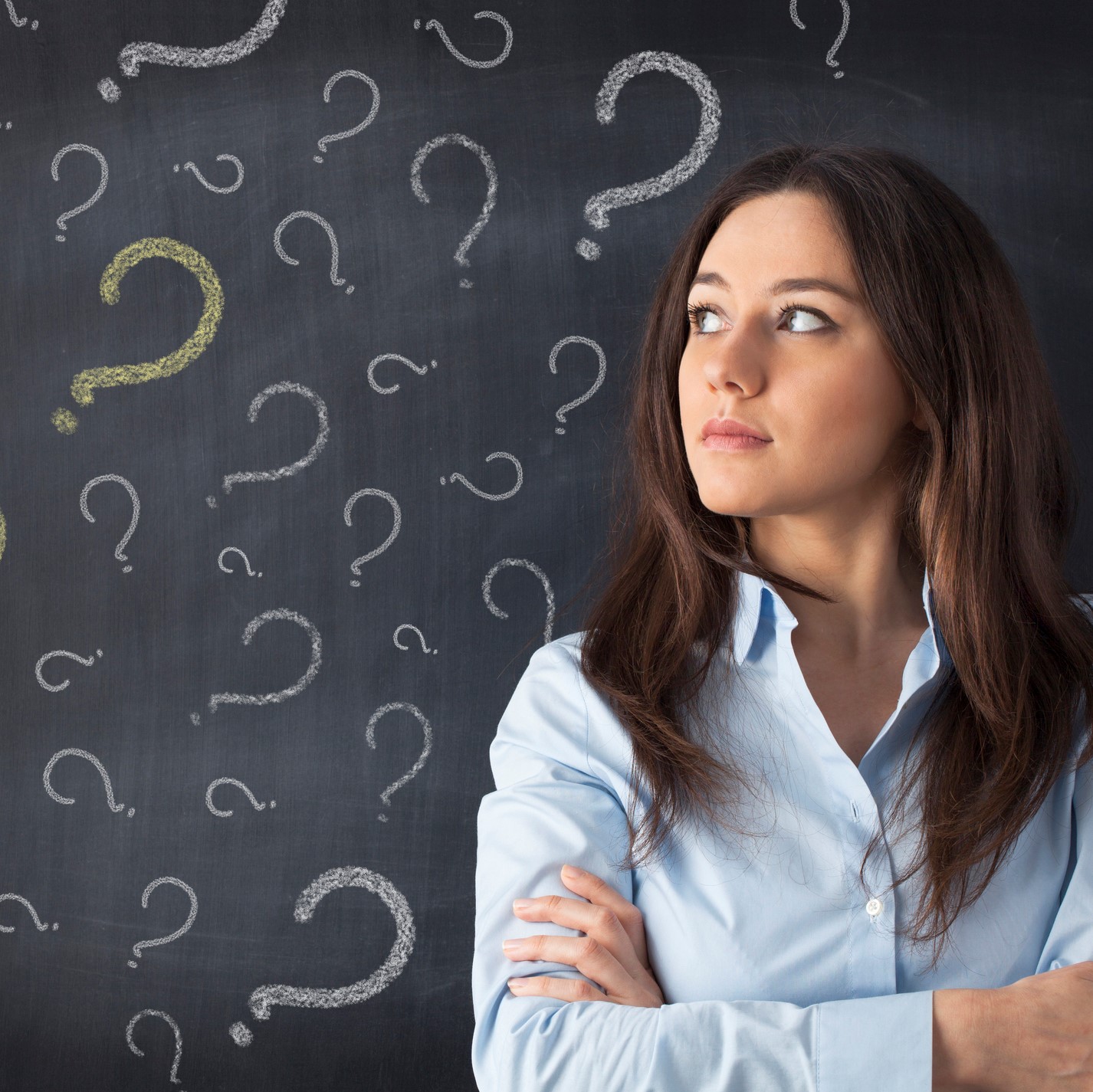 Woman in front of question marks drawn on blackboard